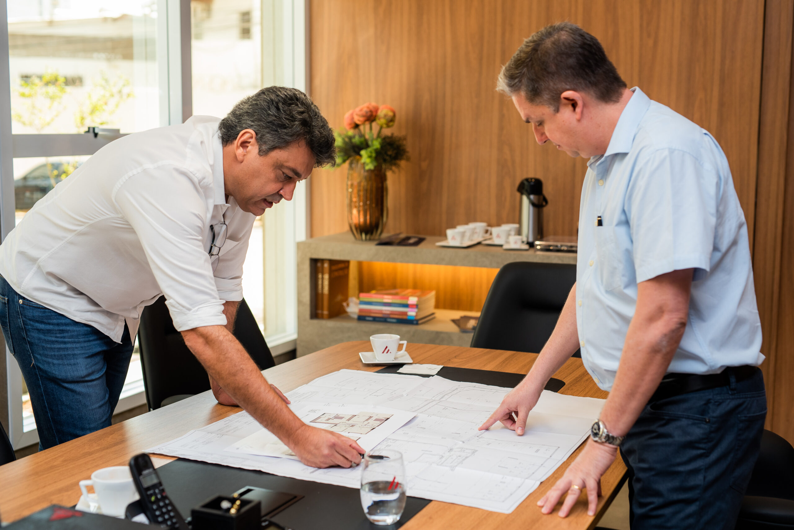 Dois sócios Empominas na sede da empresa discutindo sobre uma planta de projeto.